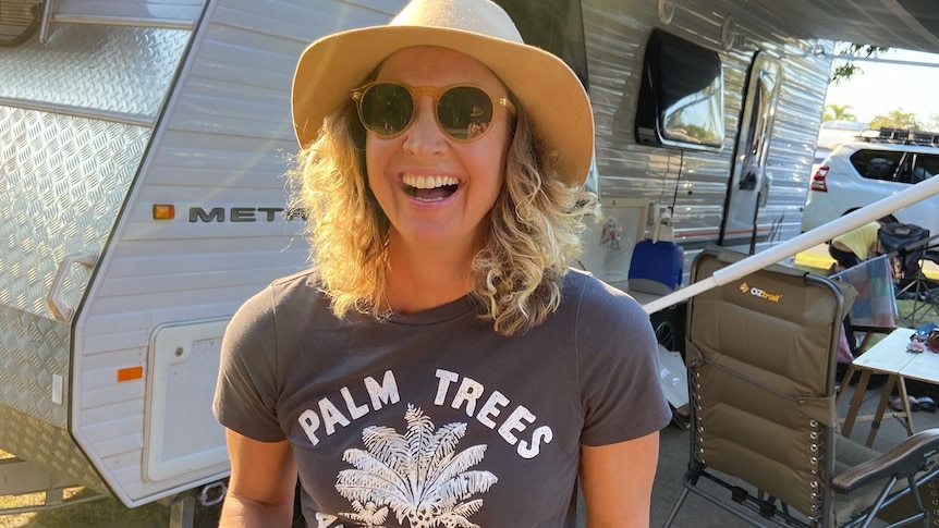 Smiling woman standing in front of caravan. 