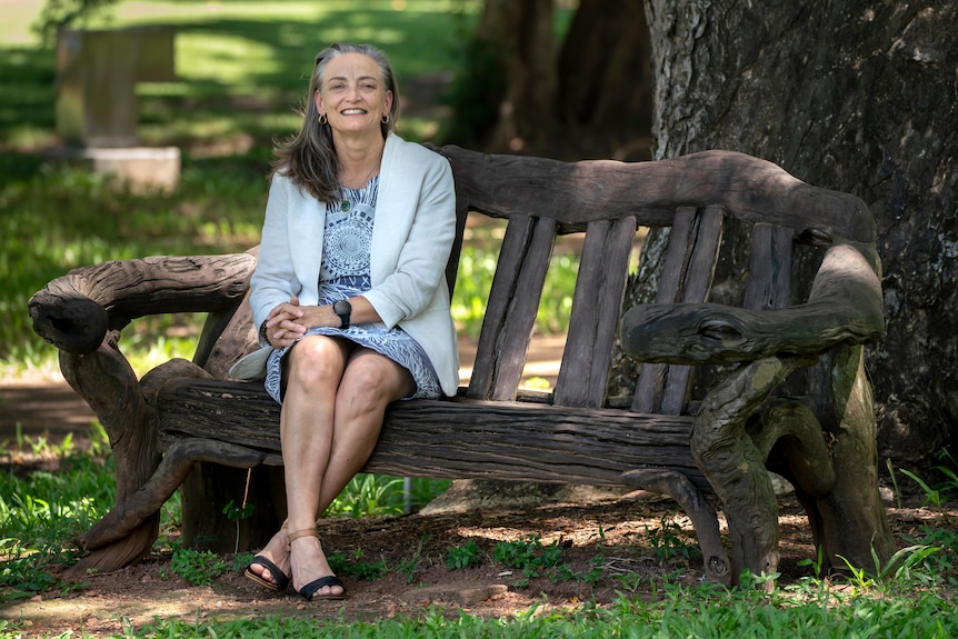 Kate Worden sits on a wooden chair and smiles at the camera.