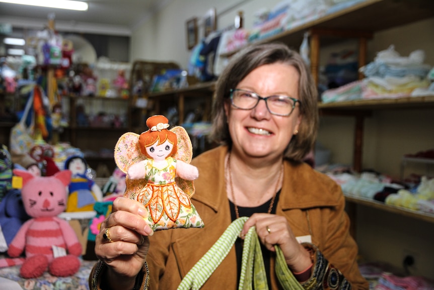 A woman holds a small fairy doll up to view