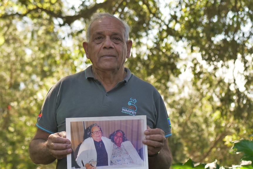 a man holds up a photograph of his mother