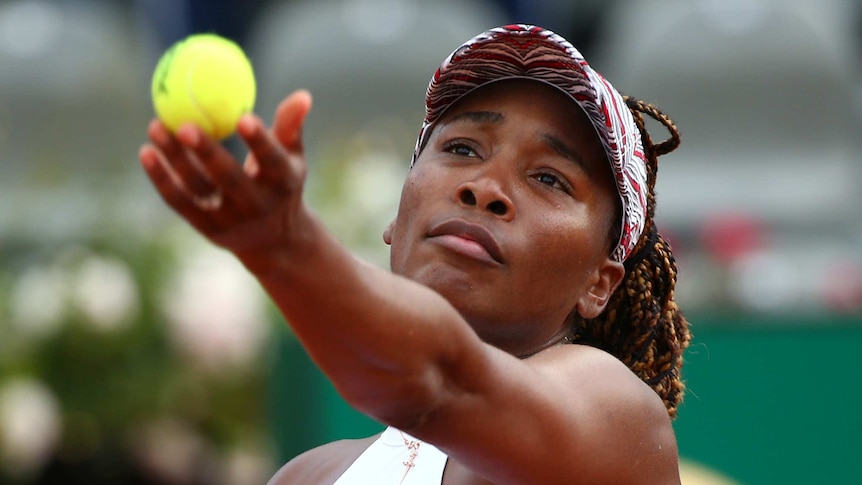 A woman begins to toss a tennis ball up in the air