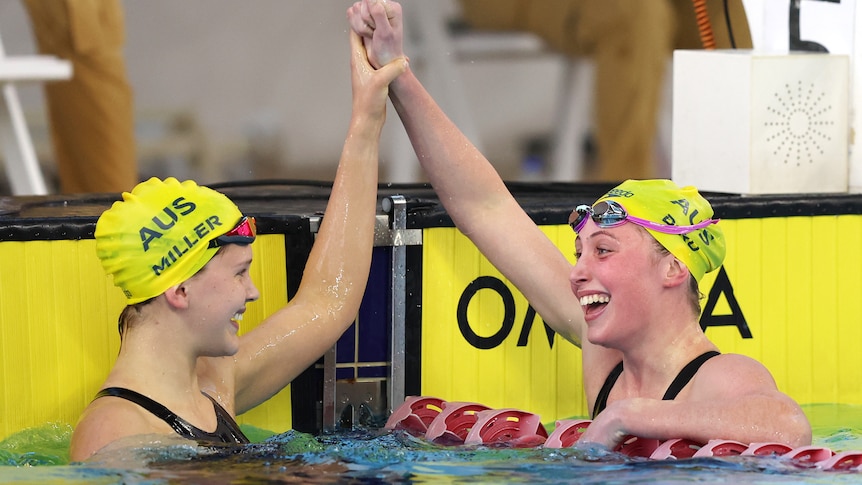 Two swimmers celebrate with each other after a race.