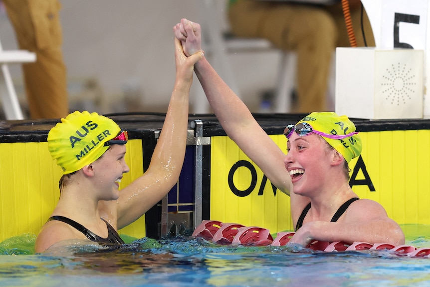 Two swimmers celebrate with each other after a race.