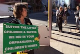 A woman holds a sign outside a hearing of the Royal Commission into Institutional Responses into Child Sexual Abuse