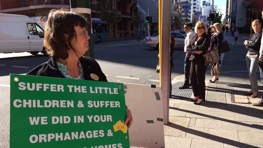 A woman holds a sign outside a hearing of the Royal Commission into Institutional Responses into Child Sexual Abuse