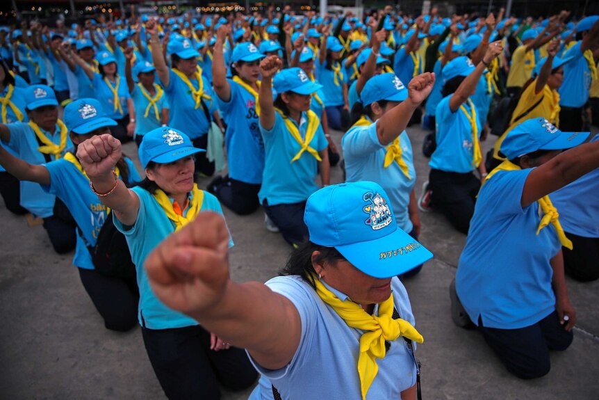 Members of the King's volunteer corps shout slogans before starting a clean-up of a Bangkok market.