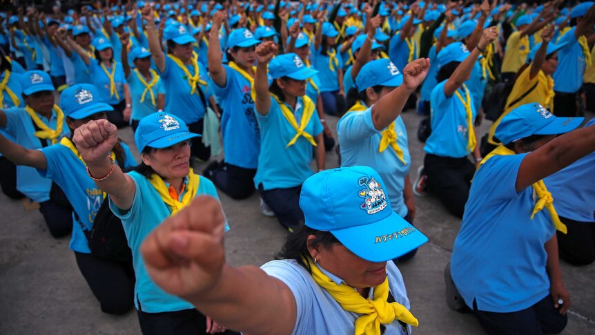 Members of the King's volunteer corps shout slogans before starting a clean-up of a Bangkok market.