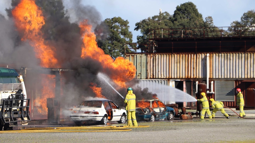 Firefighters hose down cars and a service station on fire.