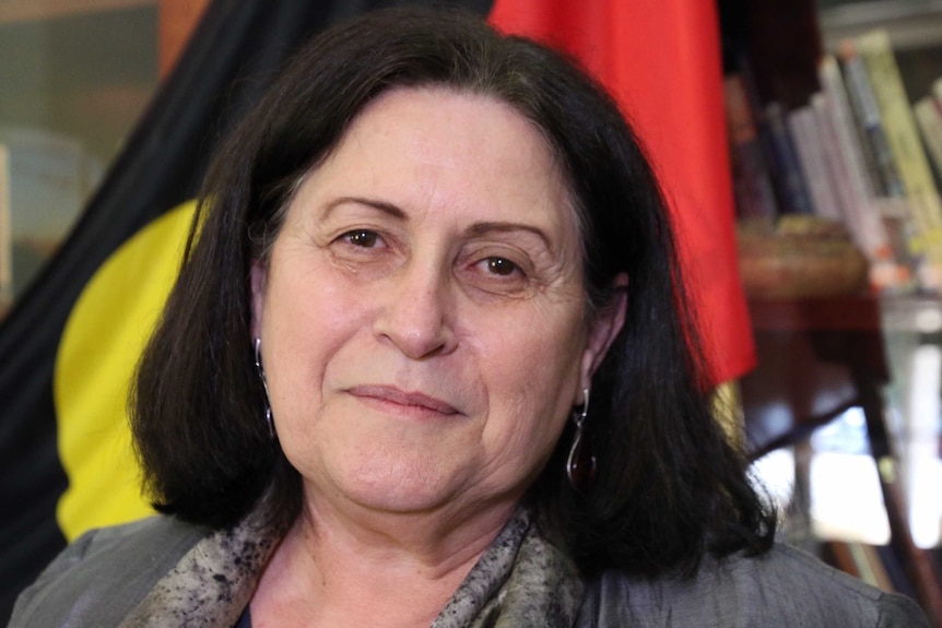 A headshot of a woman with an Aboriginal flag in the background.