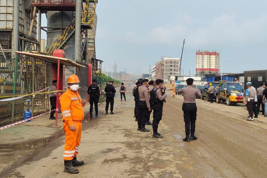 Police officers and workers stand near the site where a furnace explosion occurred a
