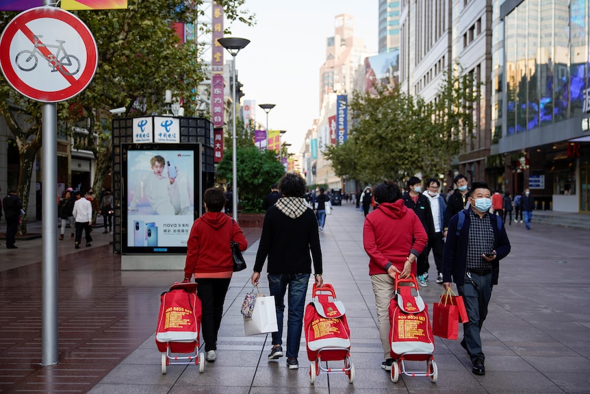 La gente camina con sus carritos de compras en una zona comercial de Shanghai
