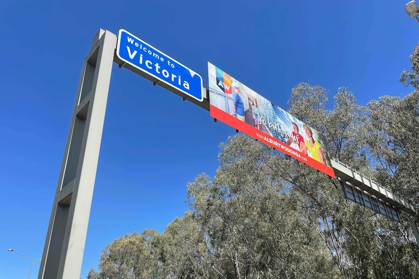 A country road with a sign above saying Welcome to Victoria