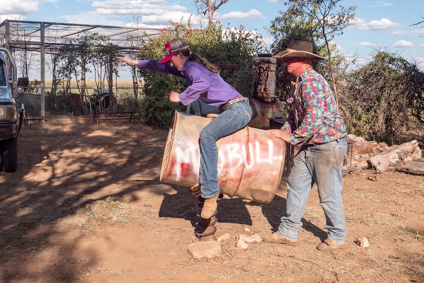 Jacy and her dad Scott practising bull riding on an old barrel, near Winton, November 2022.