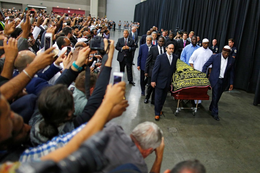 Worshipers and well-wishers take photographs as the casket of Muhammad Ali passes