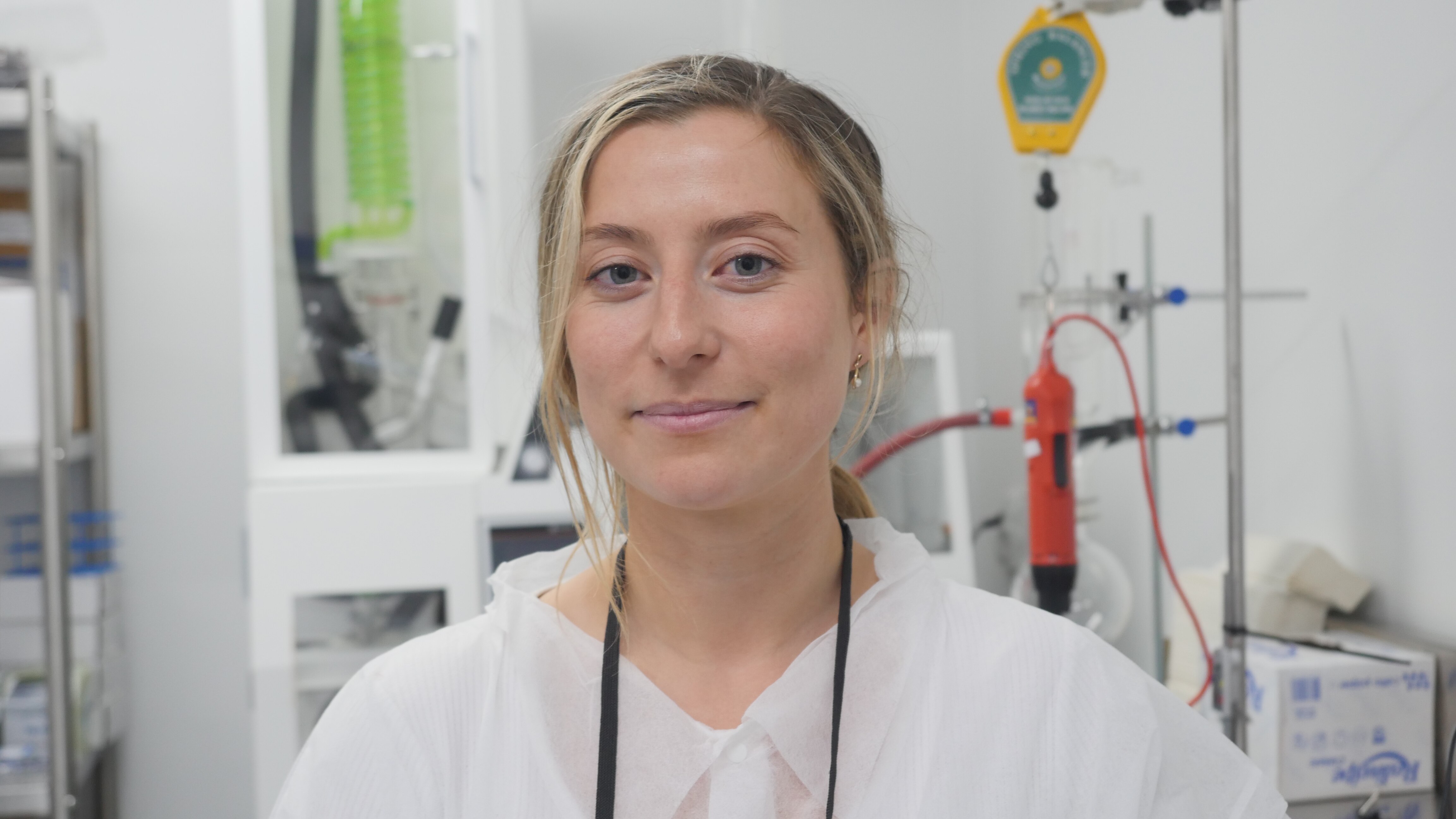 woman in hazmat suit looks at the camera from within a clean lab, machines and tools sit in the background 