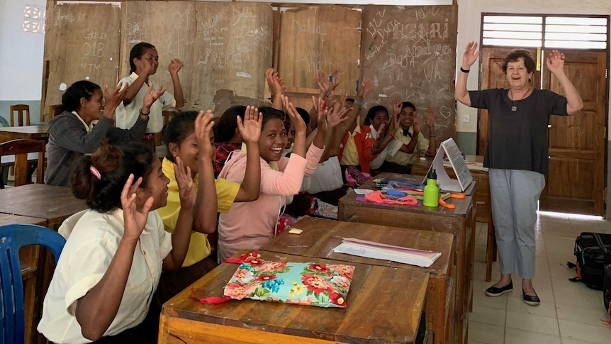 A classroom of East Timorese children shake their hands to dry them.