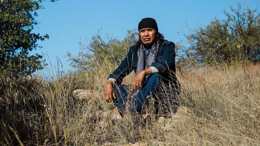 Apache elder Dr Wendsler Nosie Snr sits on the ground at Oak Flat.