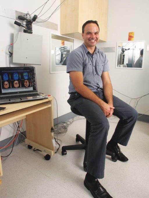 Clinical geneticist Dr Gareth Baynam sitting on a stool with medical equipment in the background.