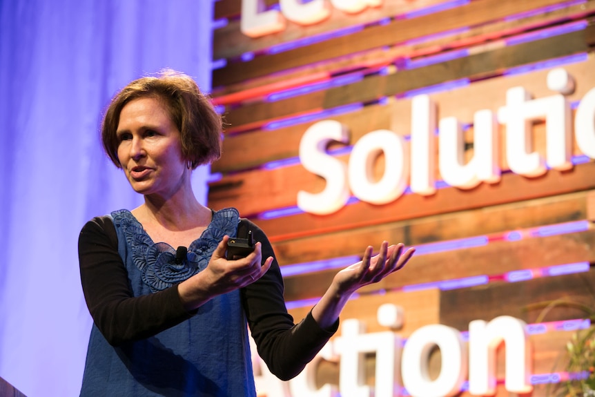 A woman speaks on stage at an event.