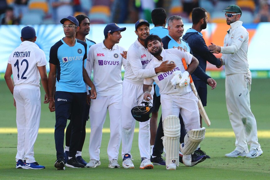 India players and support staff embrace as they celebrate beating Australia in the fourth Test in Brisbane.