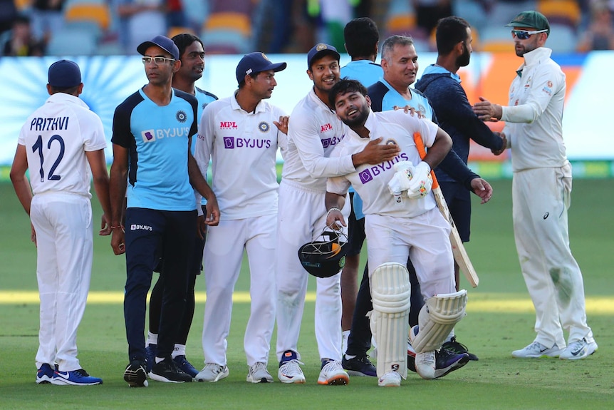 India players and support staff embrace as they celebrate beating Australia in the fourth Test in Brisbane.