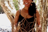 woman with straw hat smiling in front of a paperbark tree