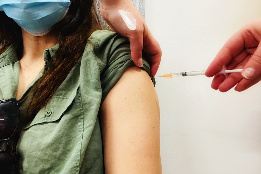 A woman's arm with a vaccine being administered into it.
