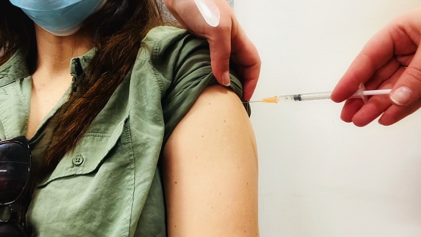 A woman's arm with a vaccine being administered into it.