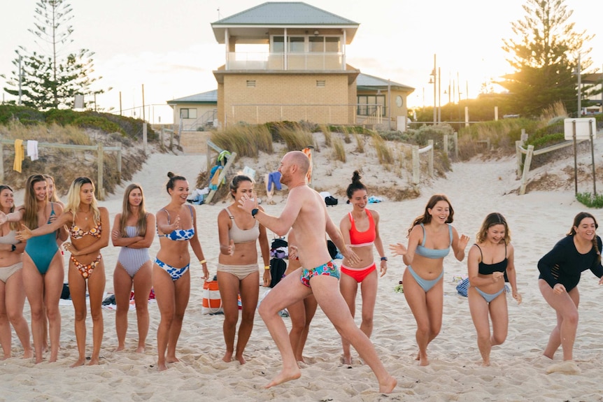 A group of girls running along the shore at Swanbourne Beach.