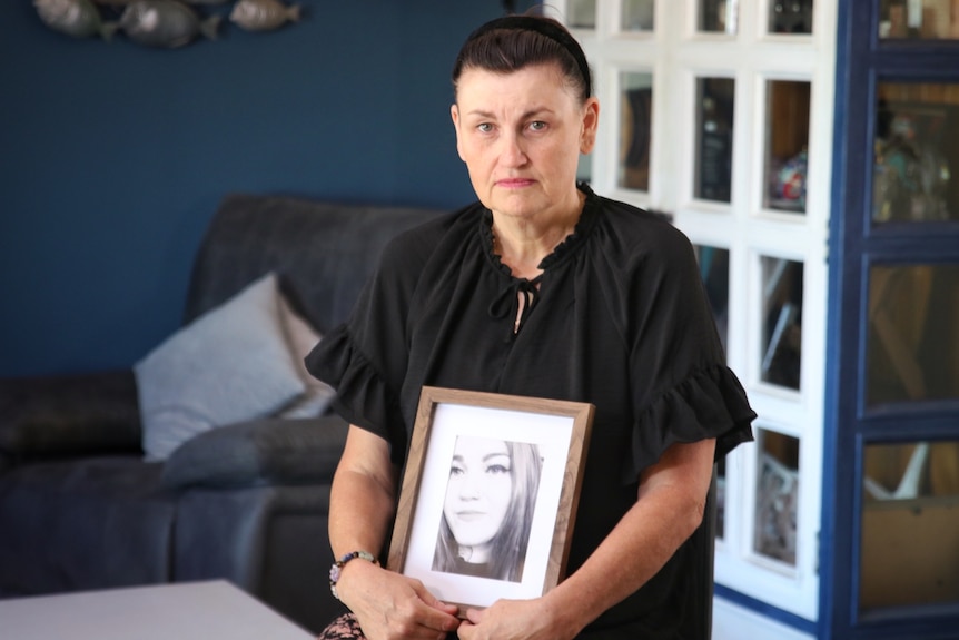 Myree holds a framed photograph of Ashley.