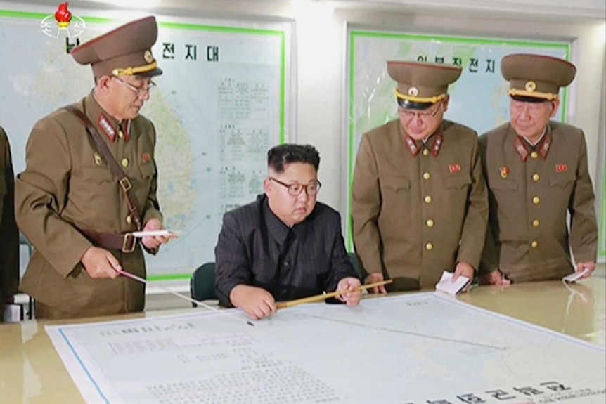 Kim Jong-un reportedly looking at plans for the proposed missile launch towards Guam. He is surrounded by military officials.