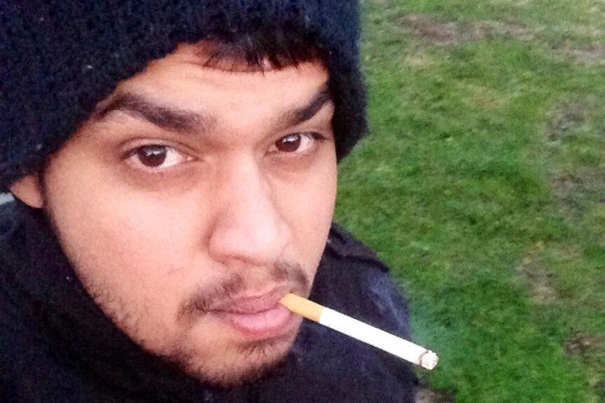 A man in a beanie with a cigarette in his mouth