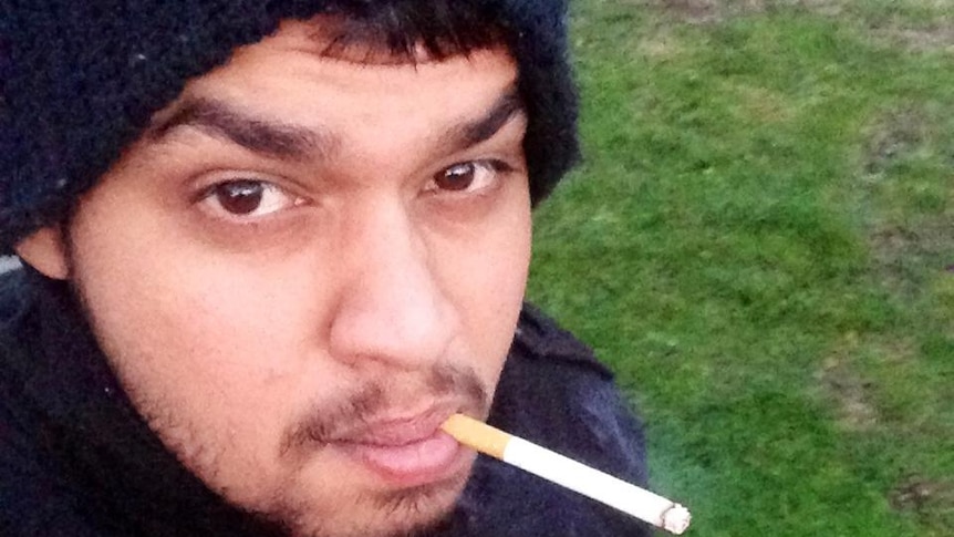 A man in a beanie with a cigarette in his mouth