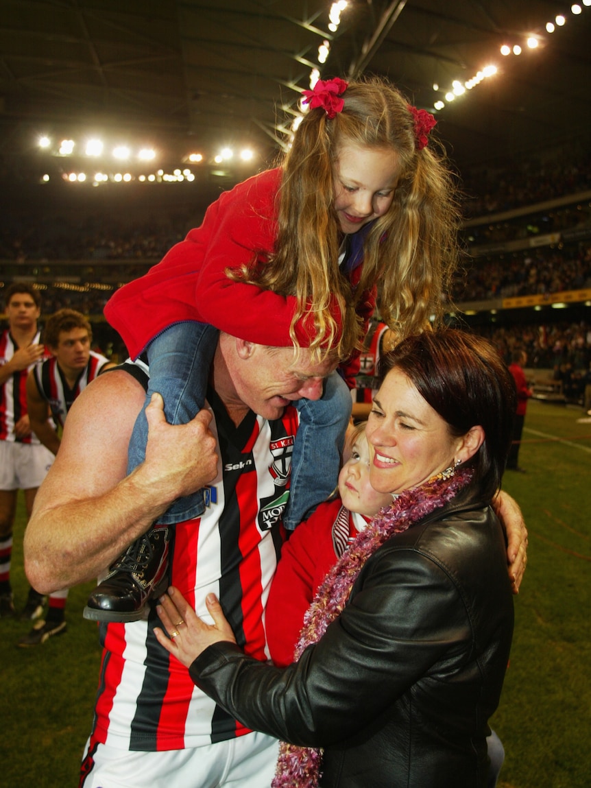 Nathan Burke holds his daughters and hugs his wife after a St Kilda game