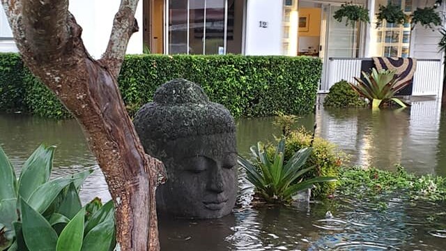 a buddha head above floodwaters in front of a real estate agent