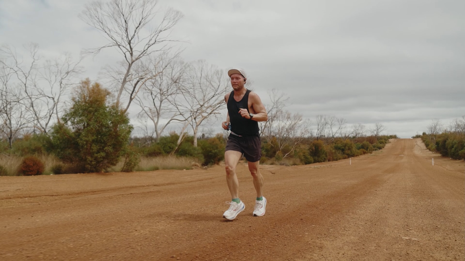Jamie wears activewear and runs along a red dirt unsealed road.