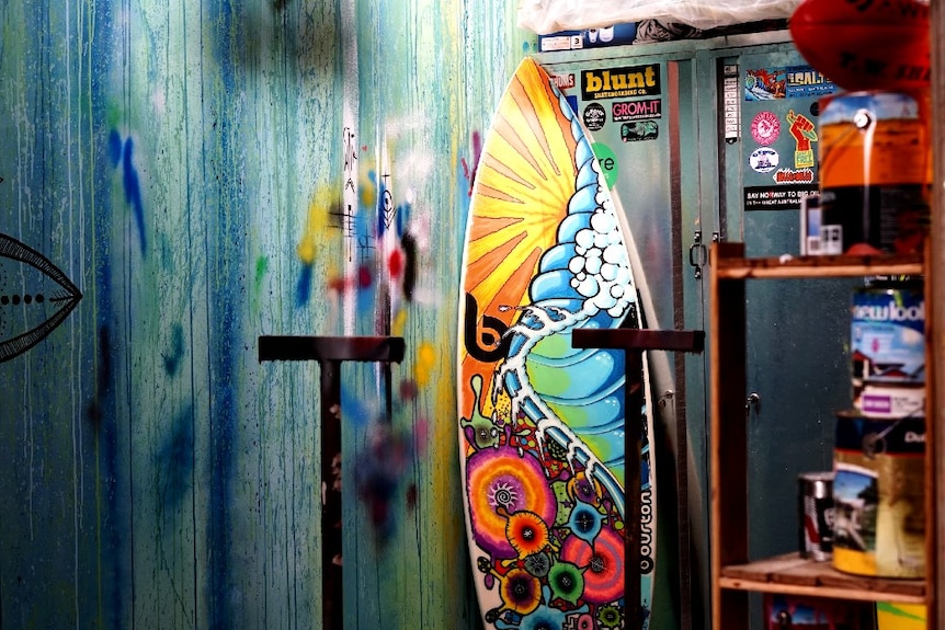 A painted surfboard resting in a drying room