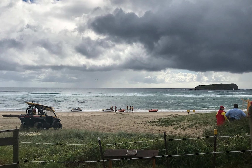 Emergency services including lifesavers, boats, helicopters, drones and police divers perform a rescue at Fingal Beach.