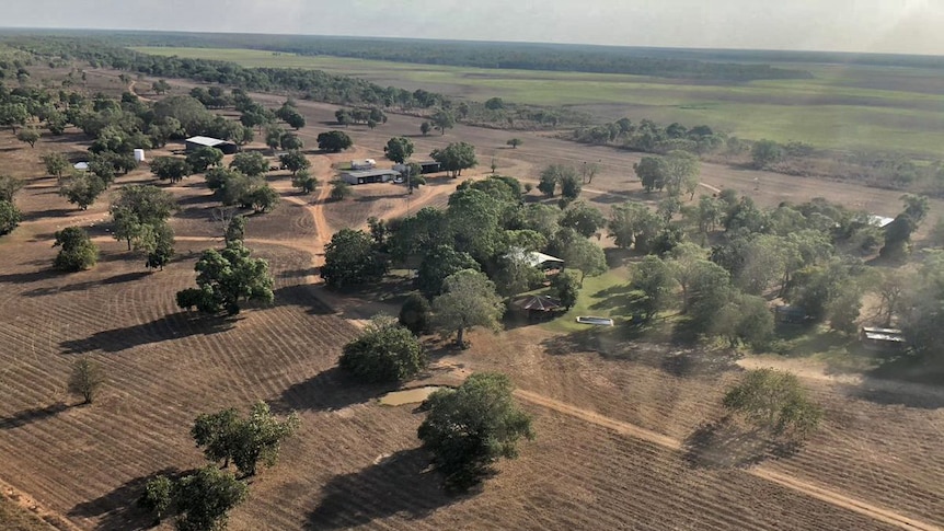 a number of buildings surrounded by trees and floodplains in the background.