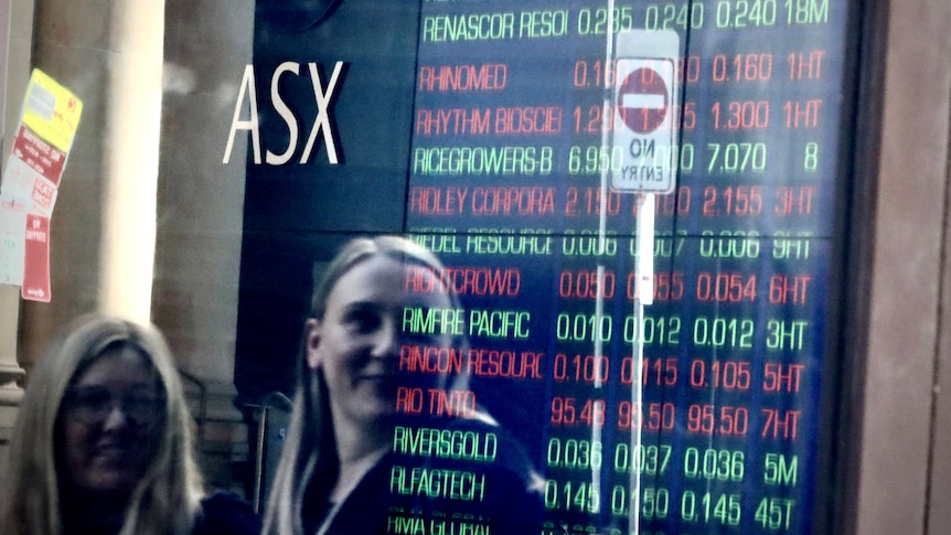 Two women look at a share price board outside the ASX in Sydney.