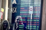 Two women look at a share price board outside the ASX in Sydney.