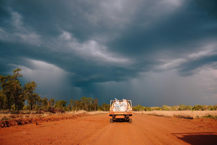 a storm on the horizon with a ute in the foreground.
