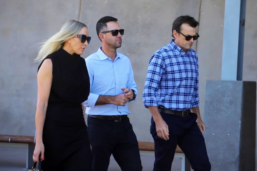 two men in shirts and sunglasses and woman with blond hair walking