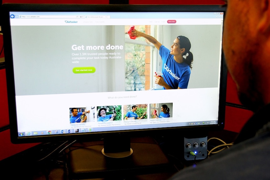 A man looks at a computer and searches on a gig platform called Airtasker