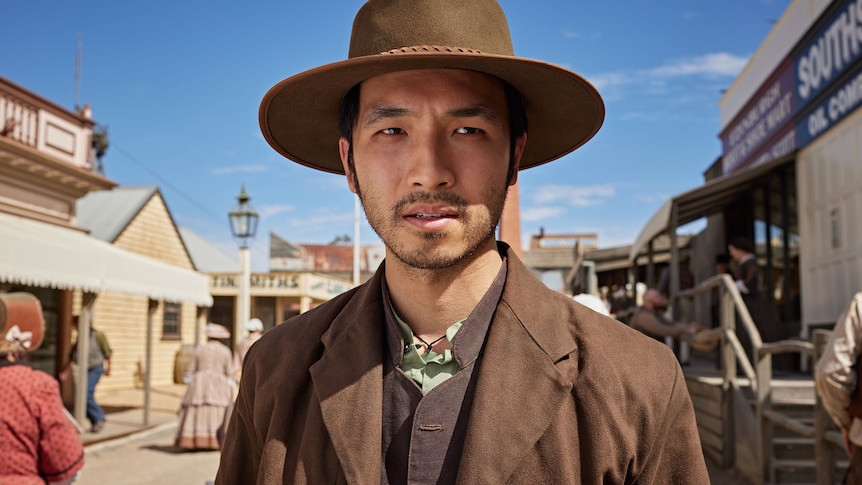 An Asian man dressed in an 1850s costume.