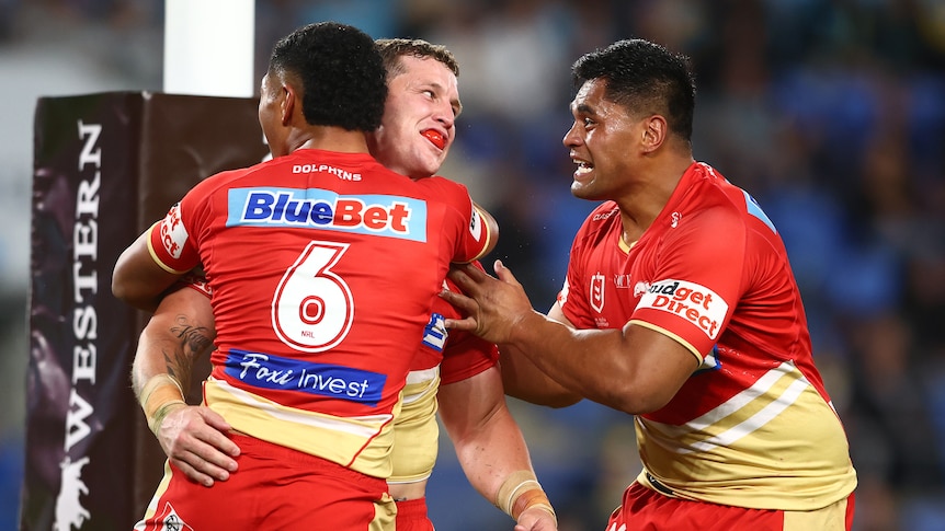 A man is hugged by teammates after scoring a try.