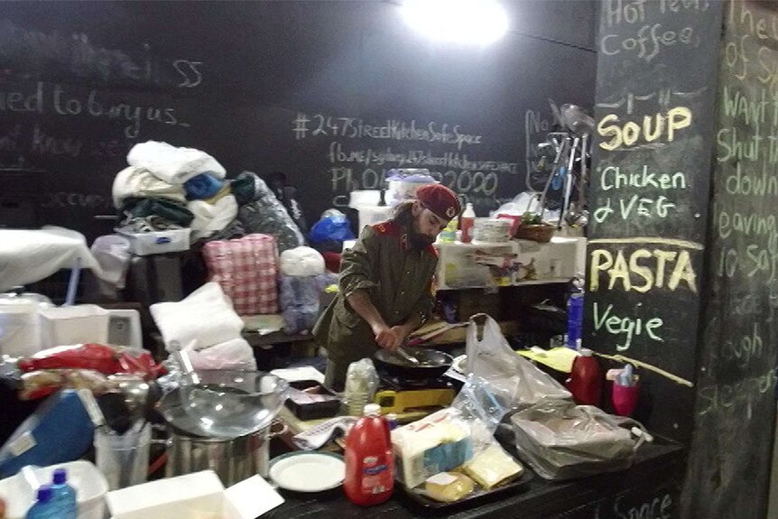 A man in a beret cooks in the street kitchen at the homeless camp in Martin Place