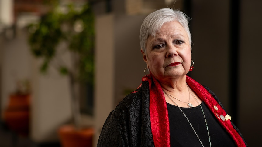 A woman wearing a red scarf looks at the camera.