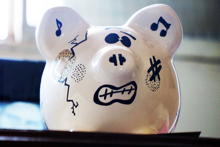 A piggy bank with cracks and bandages and a grimaced expression.