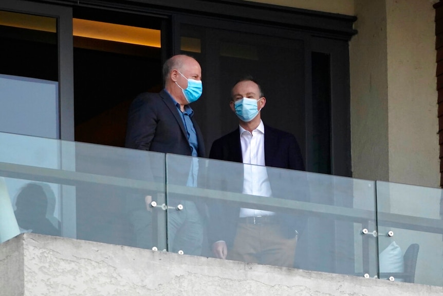 Two members of the World Health Organization team chat on a hotel room balcony in Wuhan.